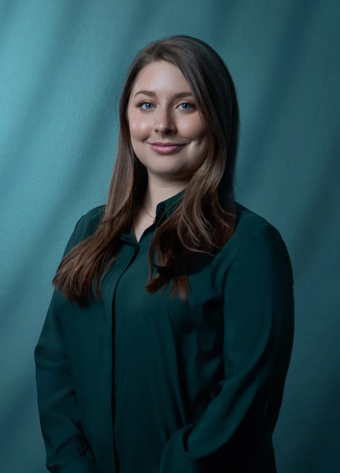 Devin Bushong of Bushong Accounting professional headshot in a dark teal blouse against a teal studio background by Unbound Collective