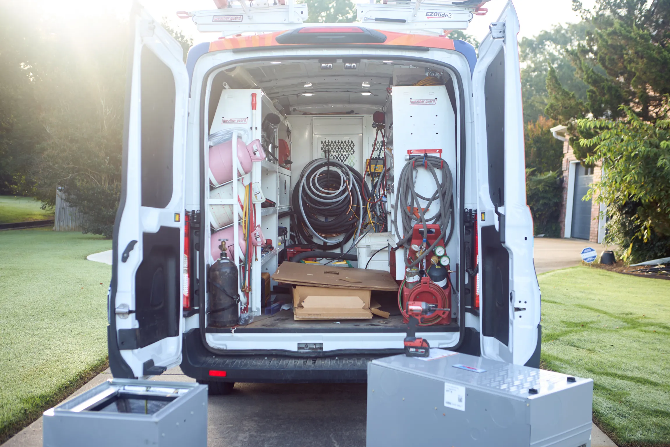 Ski Brothers HVAC branded service van with rear doors open showing fully stocked interior with refrigerant lines, gauges, and HVAC tools by Unbound Collective