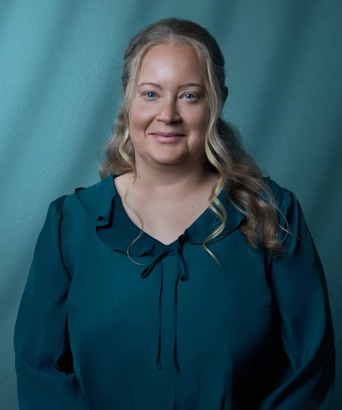Jessica Pelkey of Bushong Accounting professional headshot in a dark teal ruffled blouse against a soft teal studio background by Unbound Collective