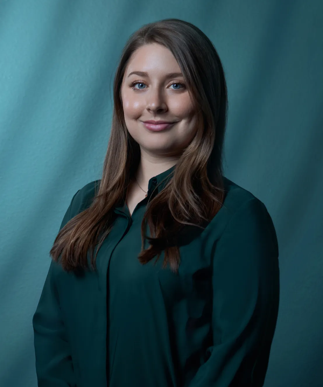 Devin Bushong of Bushong Accounting professional headshot in a dark teal blouse against a teal studio background by Unbound Collective
