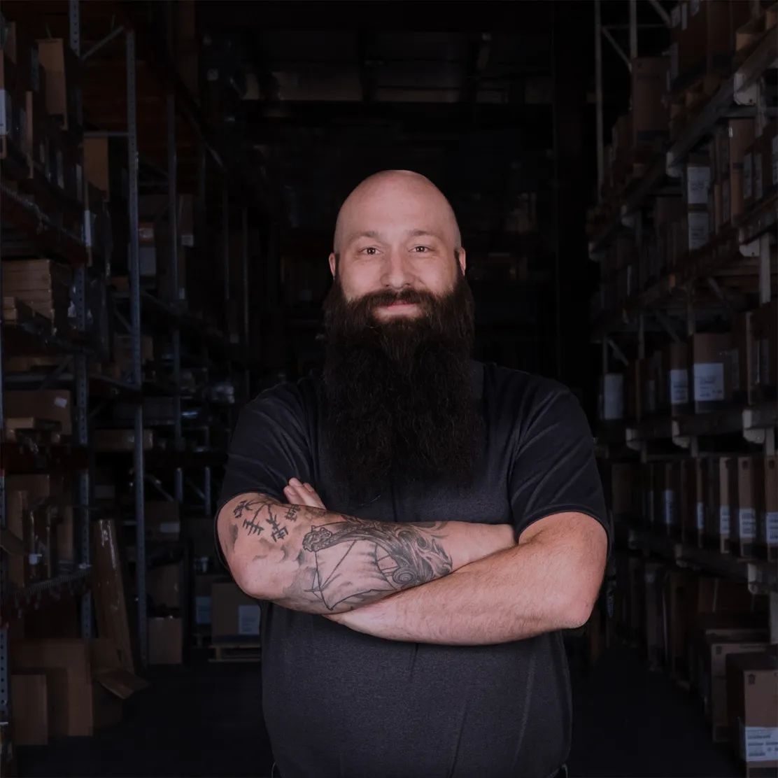 Jack Campbell Branch Manager at R&E Supply Little Rock Arkansas professional headshot with arms crossed in a dark warehouse aisle, brand photography by Unbound Collective