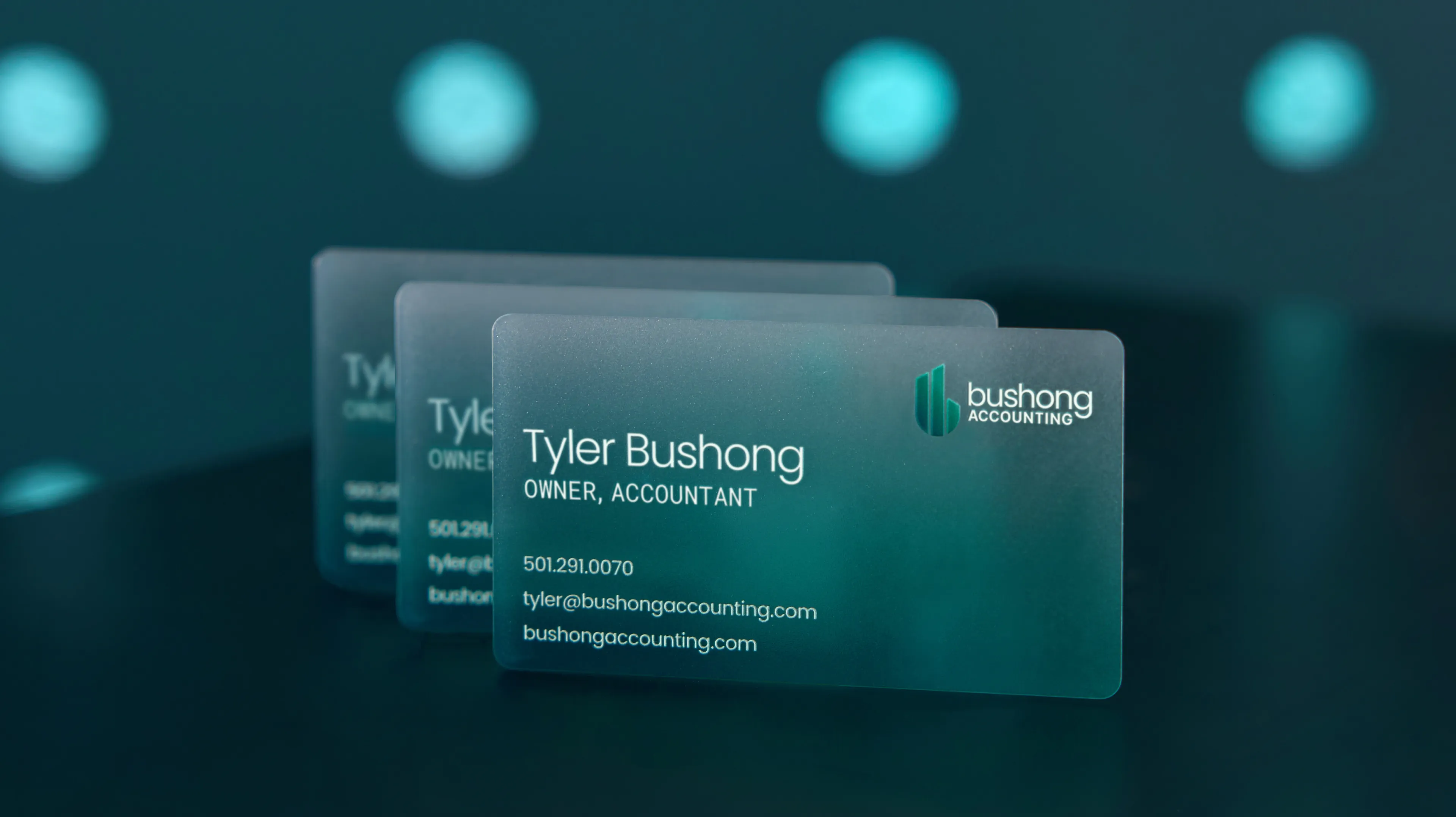 Bushong Accounting frosted teal business cards for Tyler Bushong Owner Accountant displayed in floating 3D render, print design by Unbound Collective