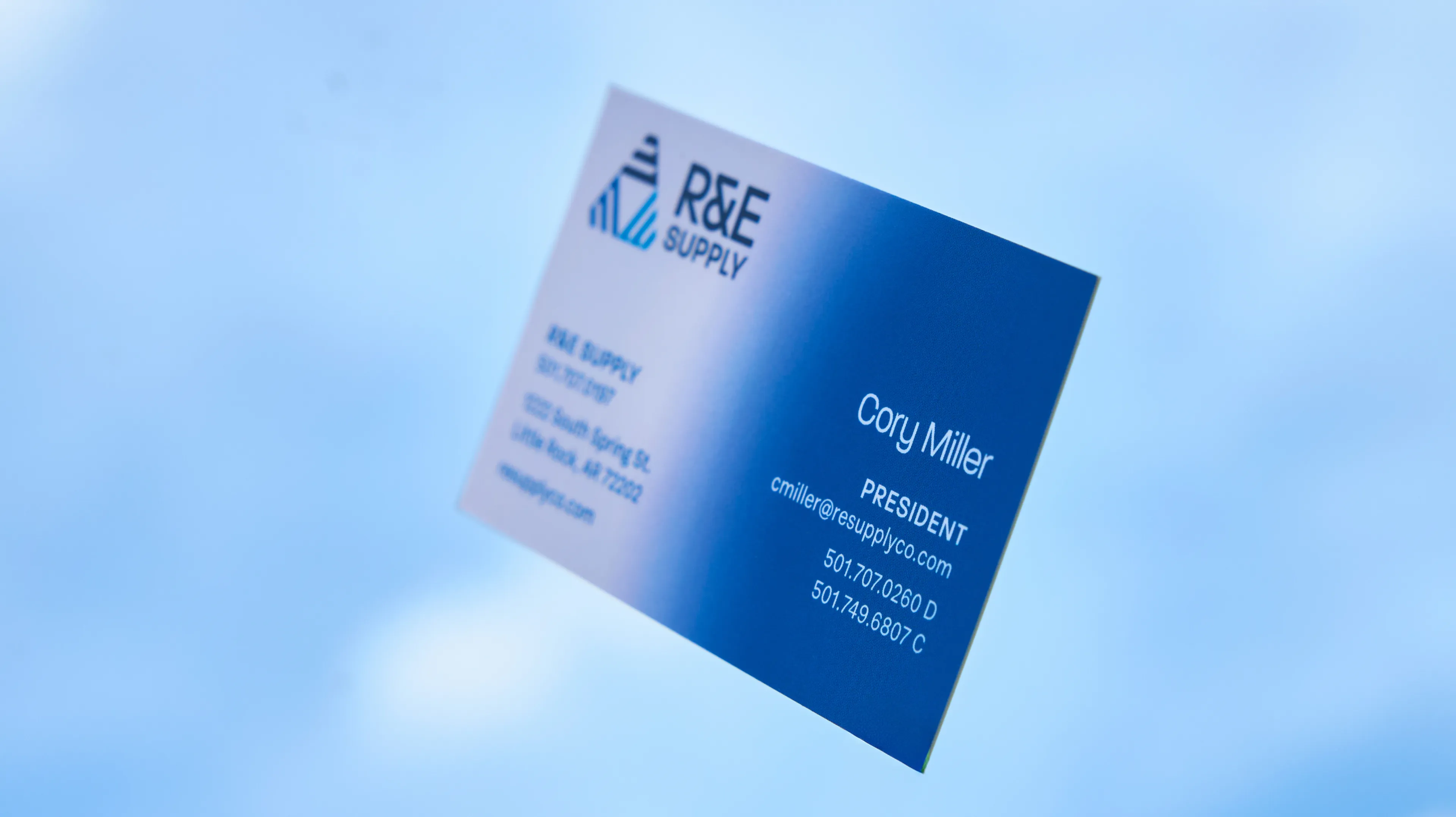 R&E Supply business card for Cory Miller President showing white to blue gradient design floating against blue sky, print design by Unbound Collective