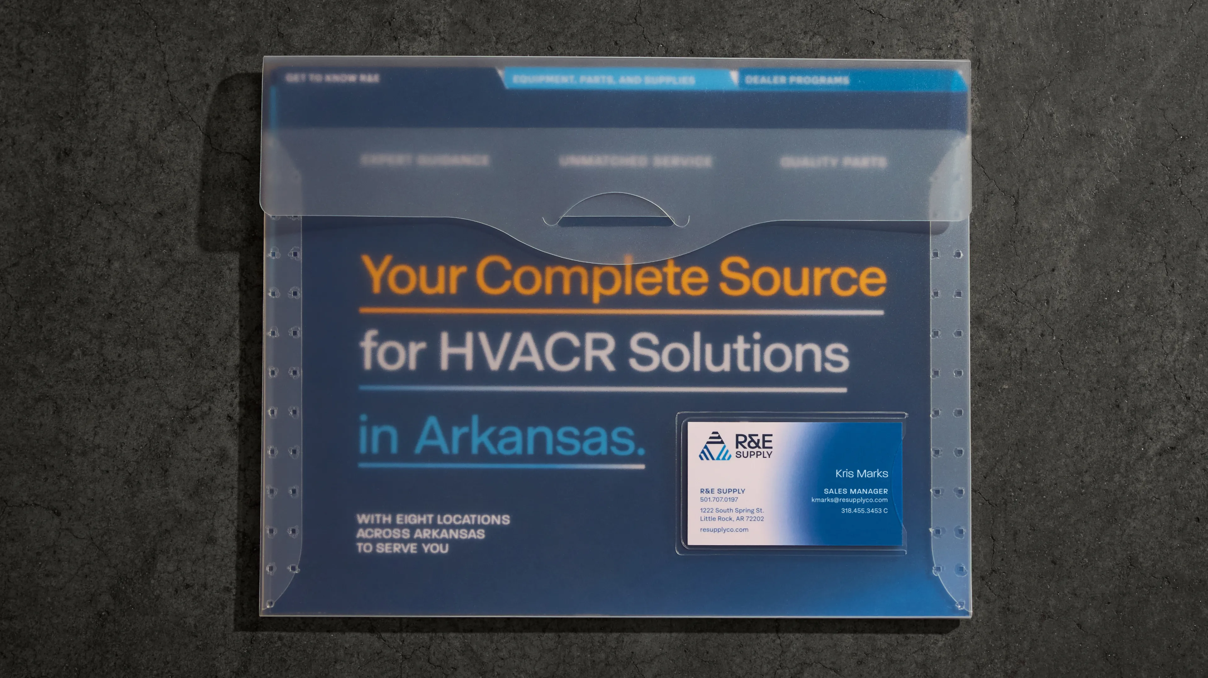 R&E Supply Your Complete Source for HVACR Solutions in Arkansas sales folder with business card tucked inside pocket on dark concrete surface, print design by Unbound Collective