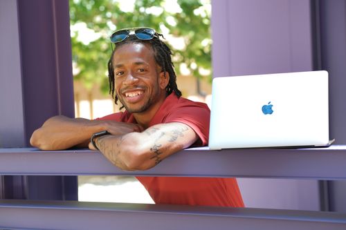 A picture of Jodi Anderson smiling next to a computer at the Stanford Graduate School of Business.