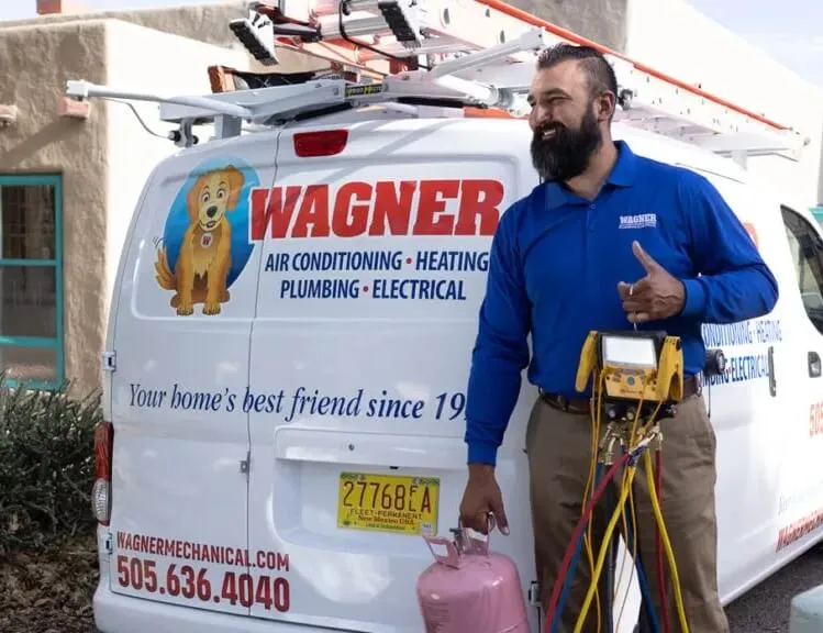 A service technician standing next to a van labeled "Wagner Air Conditioning, Heating, Plumbing, Electrical." The image shows the technician smiling and holding tools, with the company’s branded van in the background.