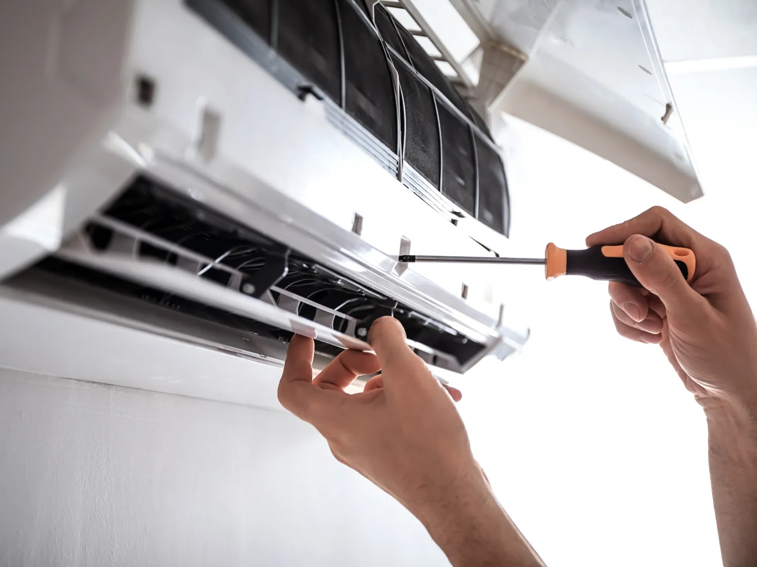 Ductless ac being inspected and repaired with a screwedriver