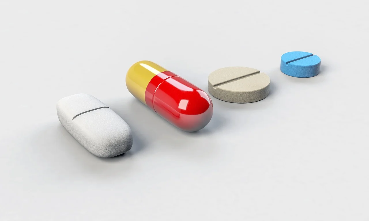 Various pills and a capsule arranged on a plain background