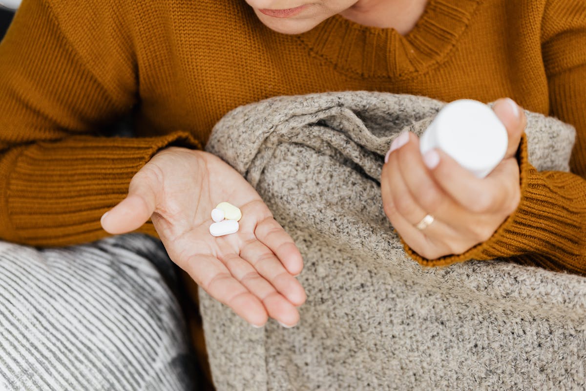 Person holding tablets in one hand while sitting with a blanket.