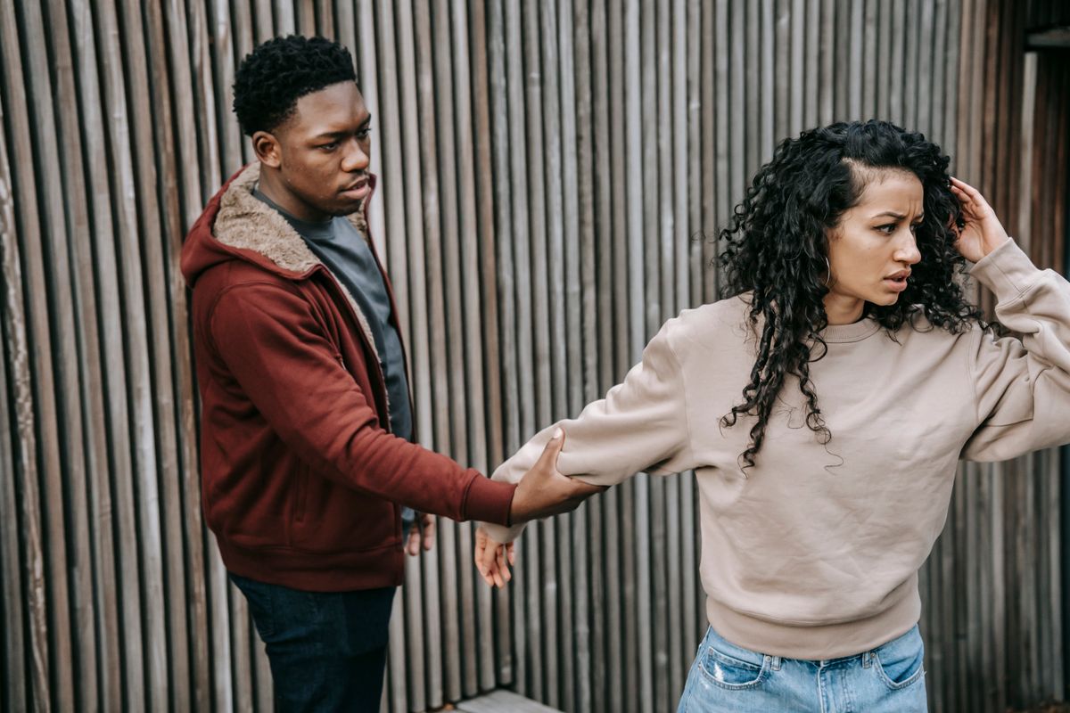 A man holding a woman by her arm as she attempts to walk away.