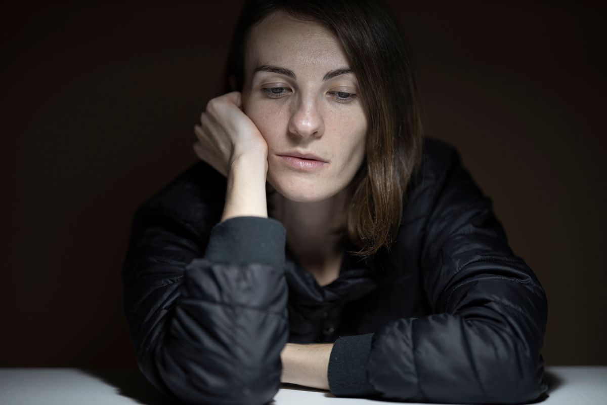 A person sitting with their head resting on their arm.