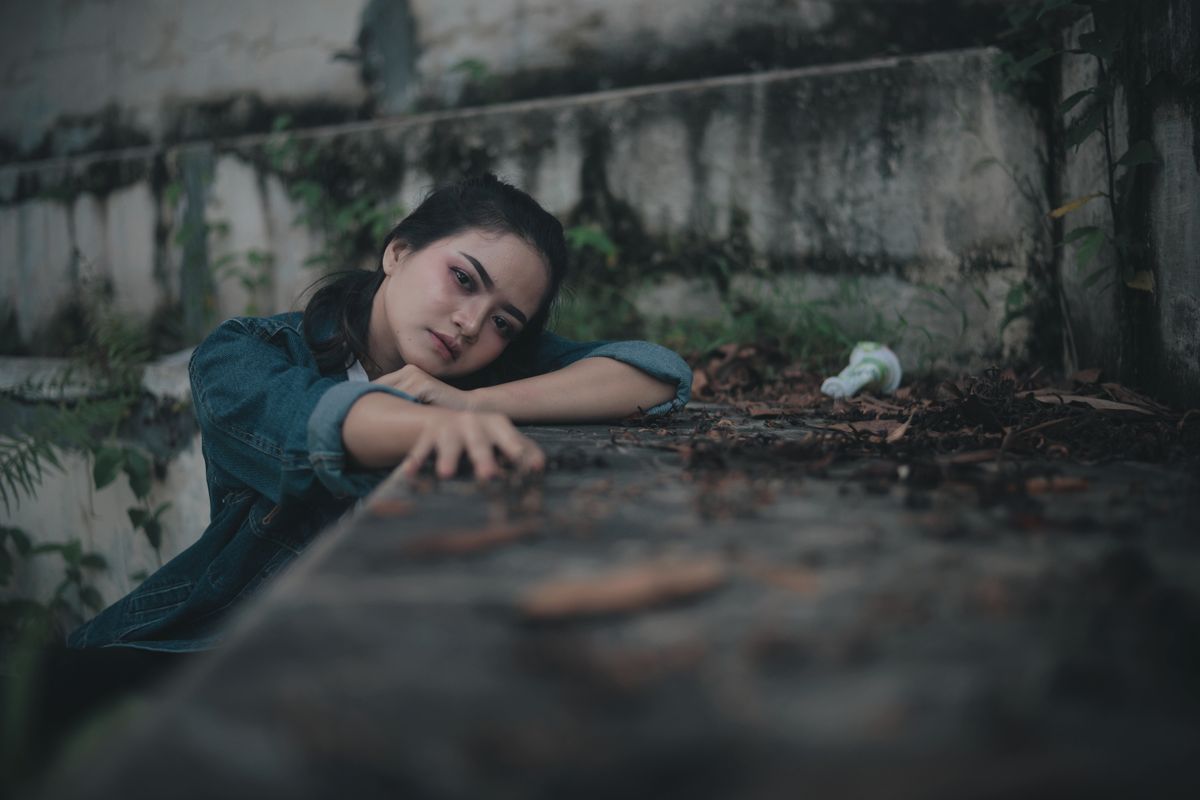 A teen appearing contemplative while leaning on a stone surface.