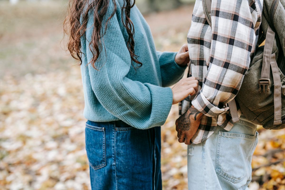 A couple sharing a tender moment in a park during the fall.
