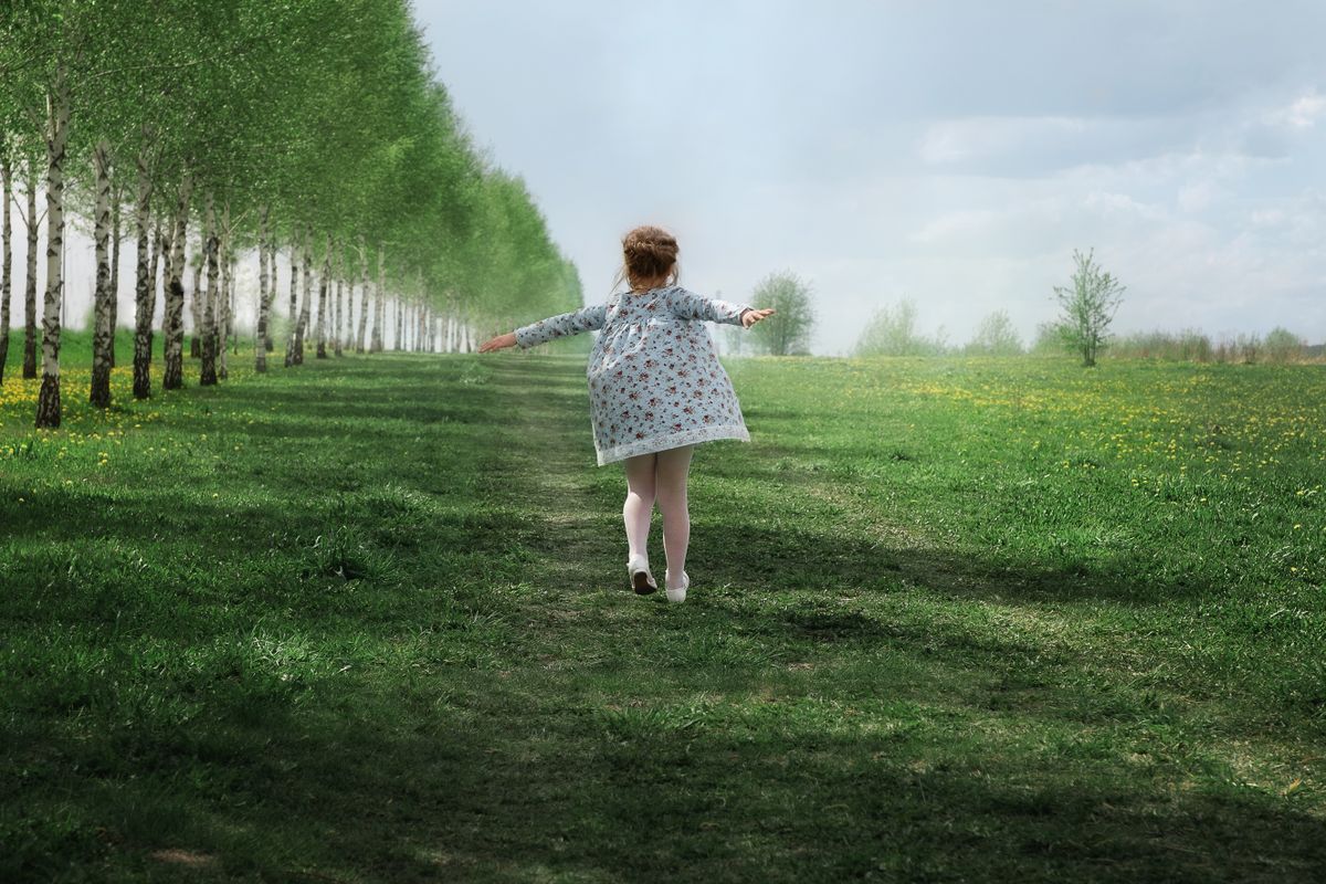 A girl in floral dress walking on a grassy field