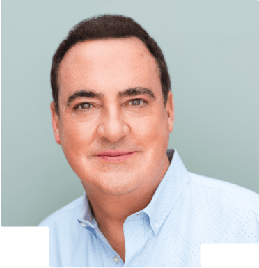 Portrait of a man with dark hair wearing a light blue collared shirt against a light gray background.