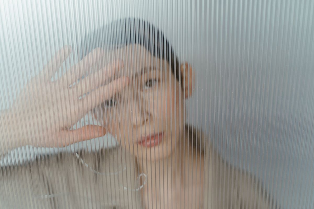 A person looking through a textured glass pane.
