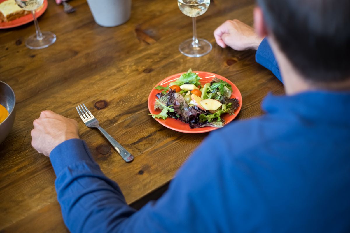 A person eating a salad from a clear bowl
