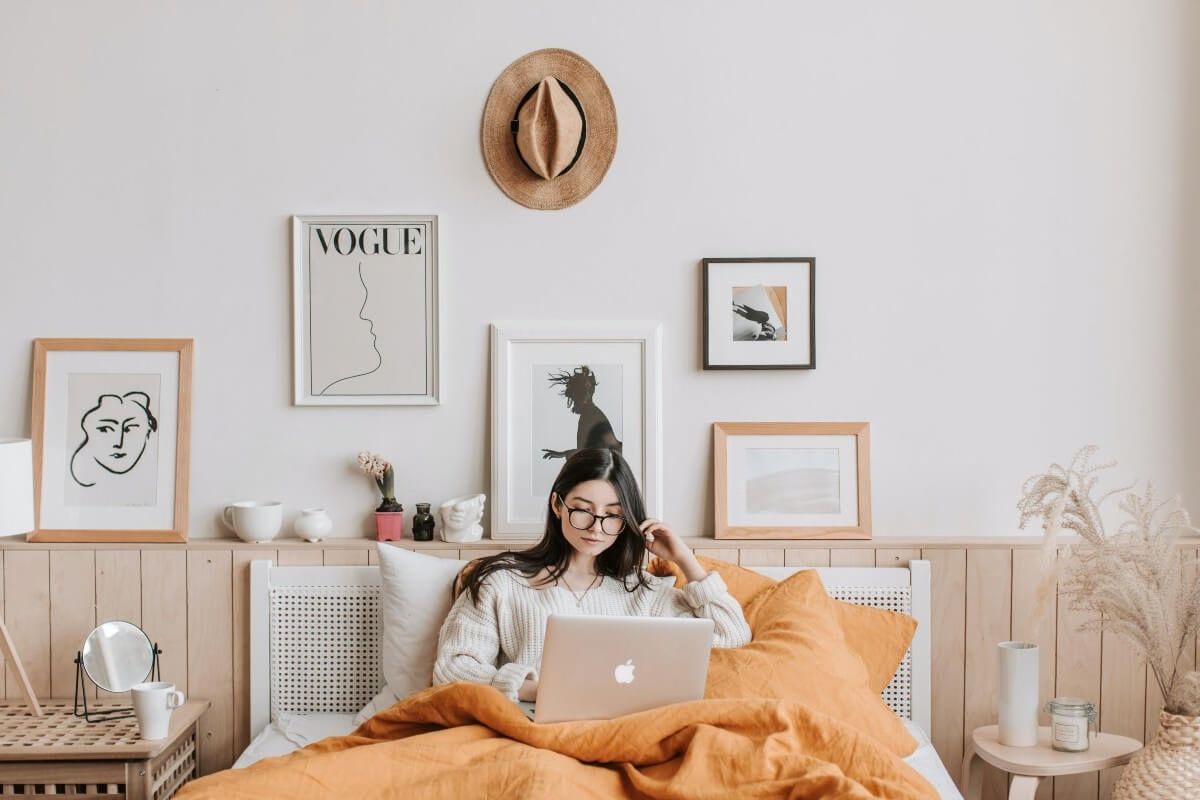 This image shows a cozy bedroom with a person using a laptop in bed.