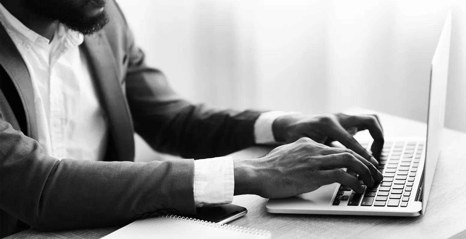 Business man sitting at a desk typing on a laptop