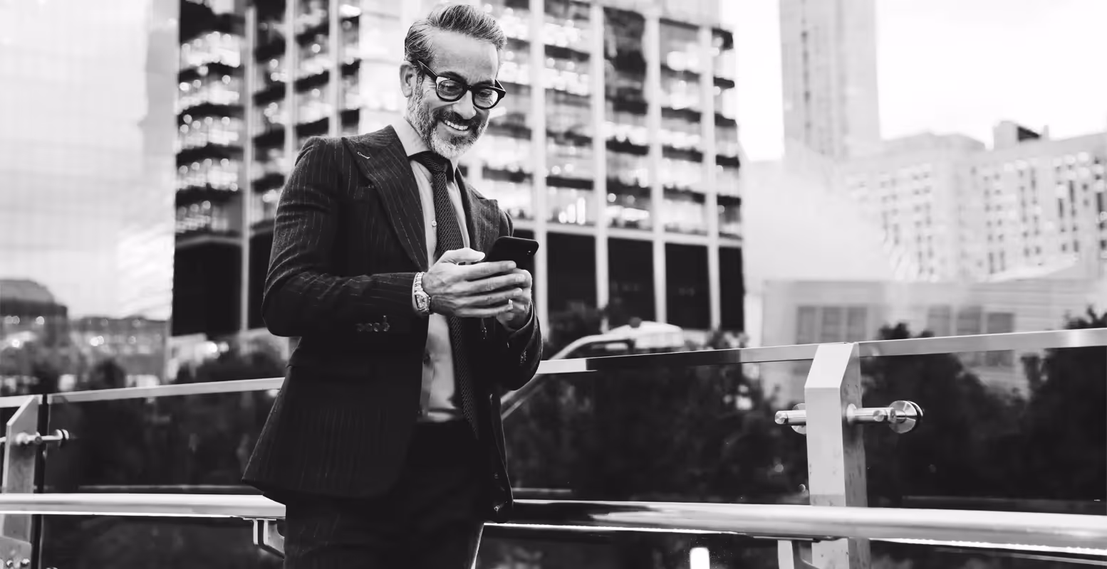 Older business man walking in city on cellphone