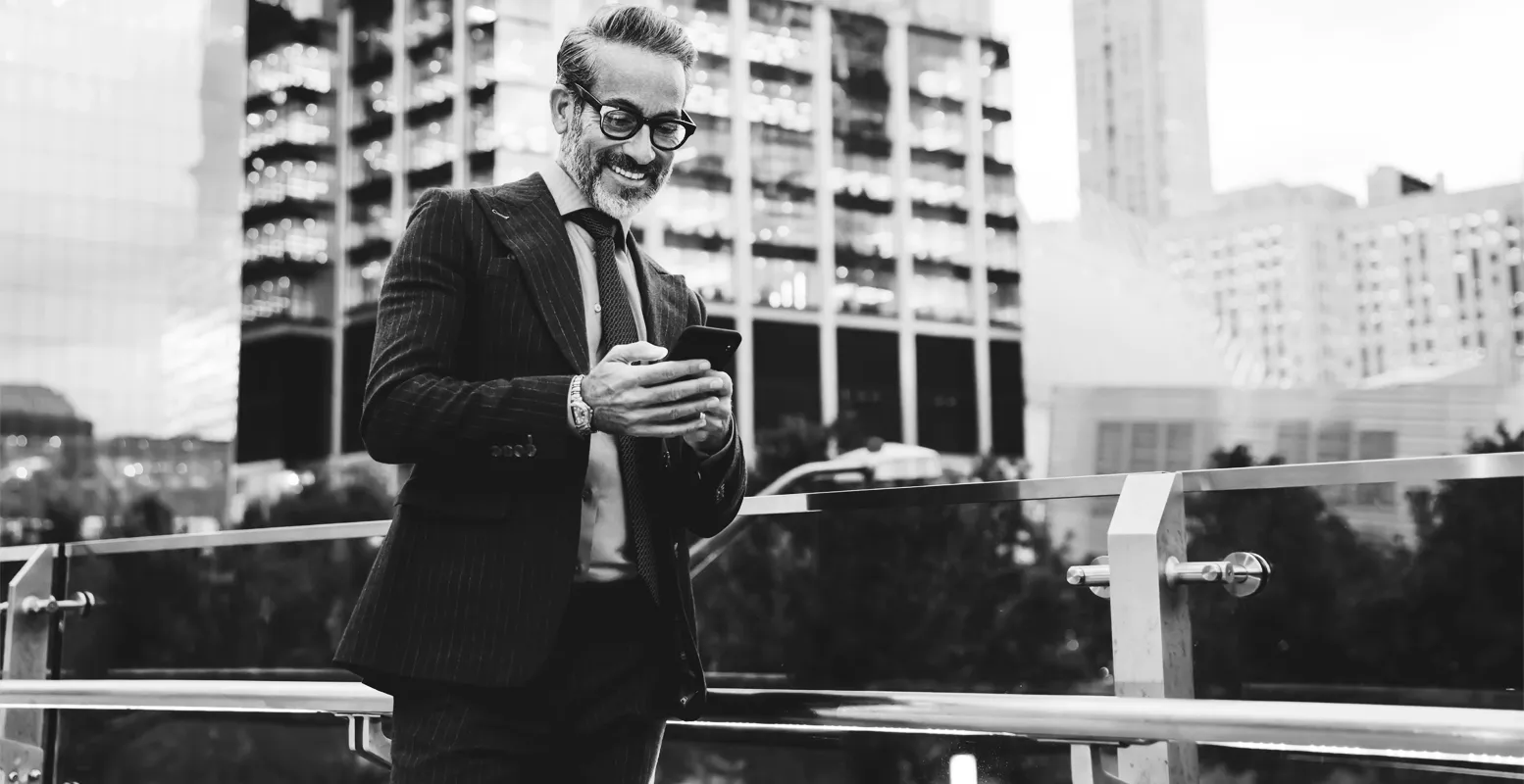 Older business man walking in city on cellphone