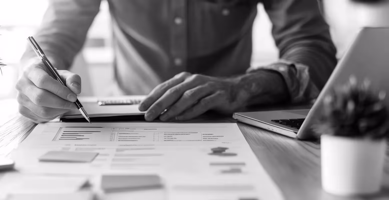 Businessman at a desk checking items off a list of papers