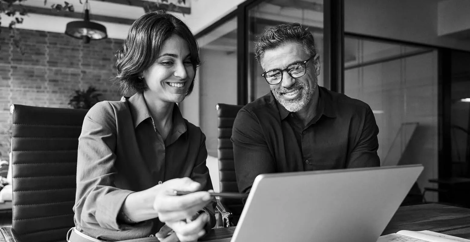 Marketer discussing project with teammate at laptop