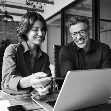 Marketer discussing project with teammate at laptop
