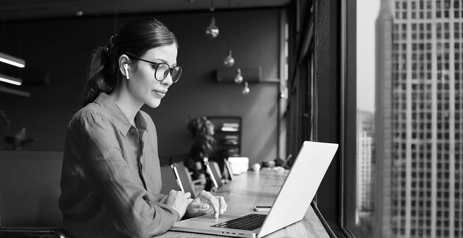 Female marketing professional working on computer looking out a window