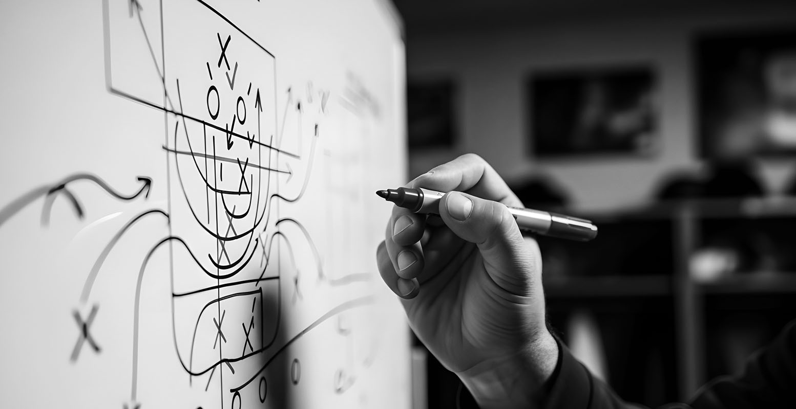 Coach writing a play with X's & O's on a whiteboard