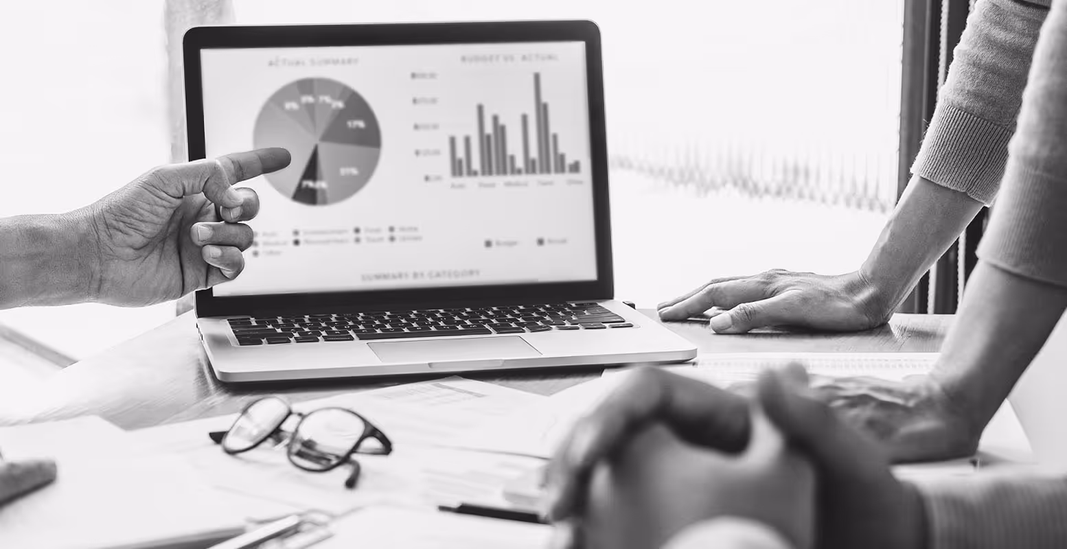 Group of business people looking at computer with charts and graphs