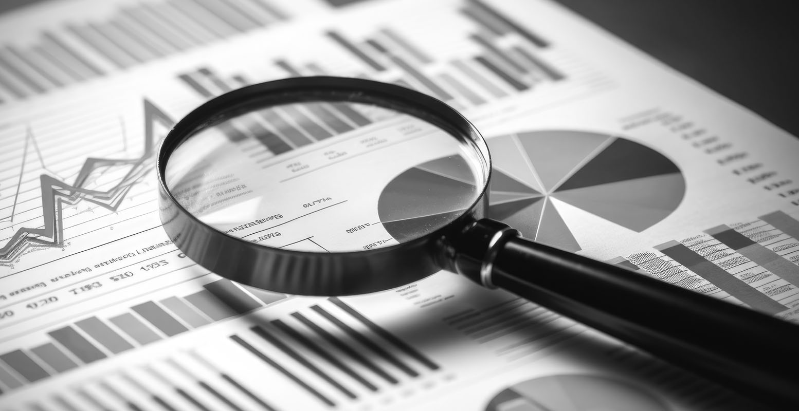 Magnifying glass sitting on top of papers with charts and graphs