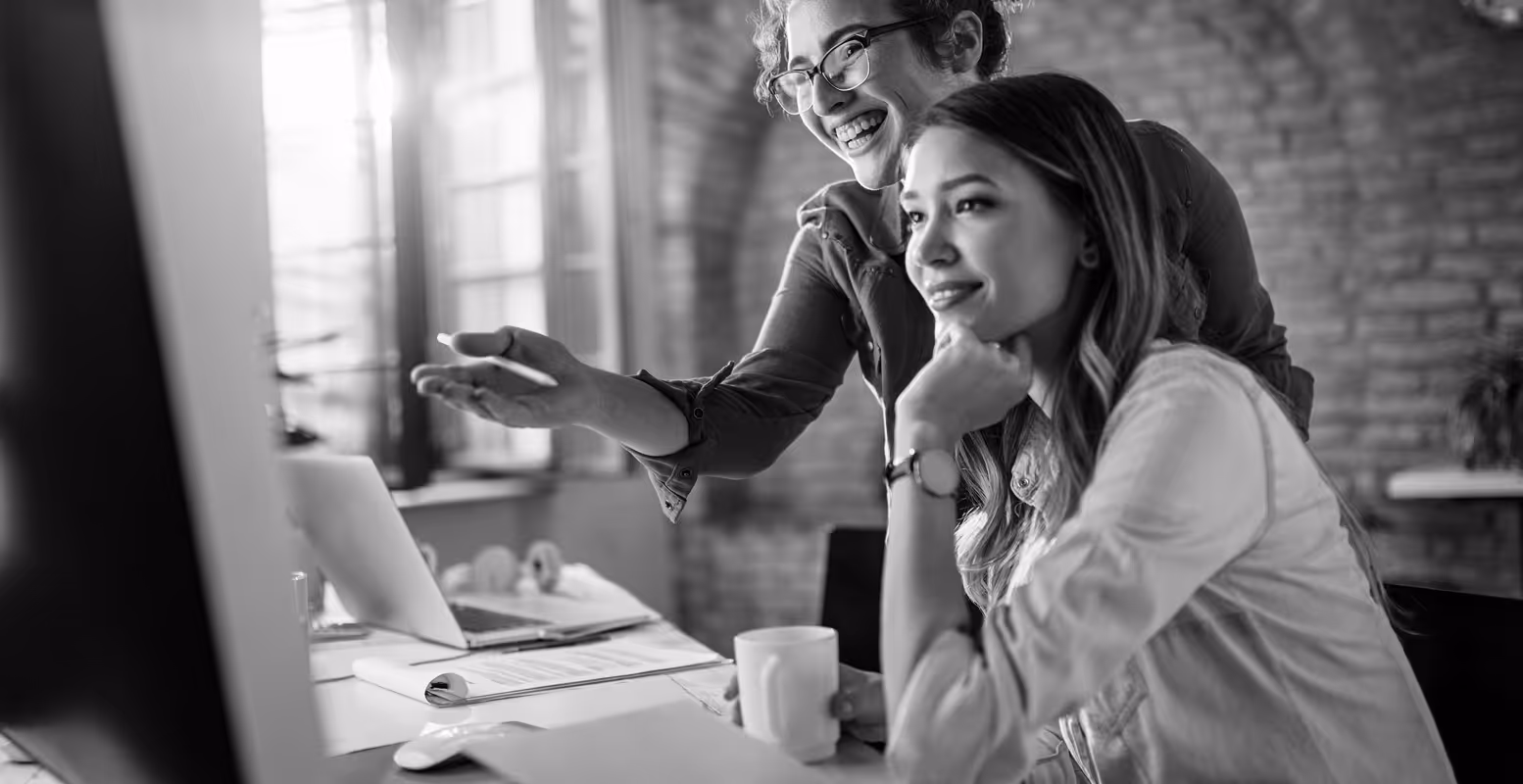 Two women professionals smiling looking at a computer