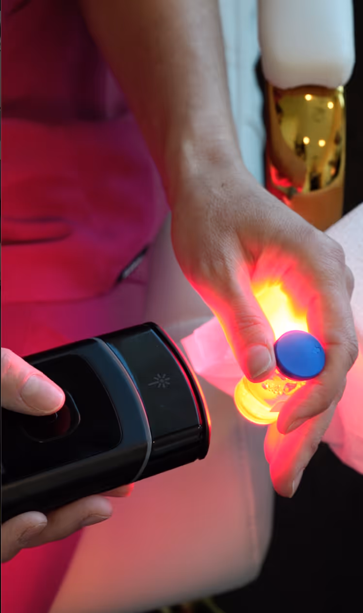 A person sitting in a chair with lasers pointed around his upper abdomen, head, and neck while they are engaging in extracellular vesicle treatment.