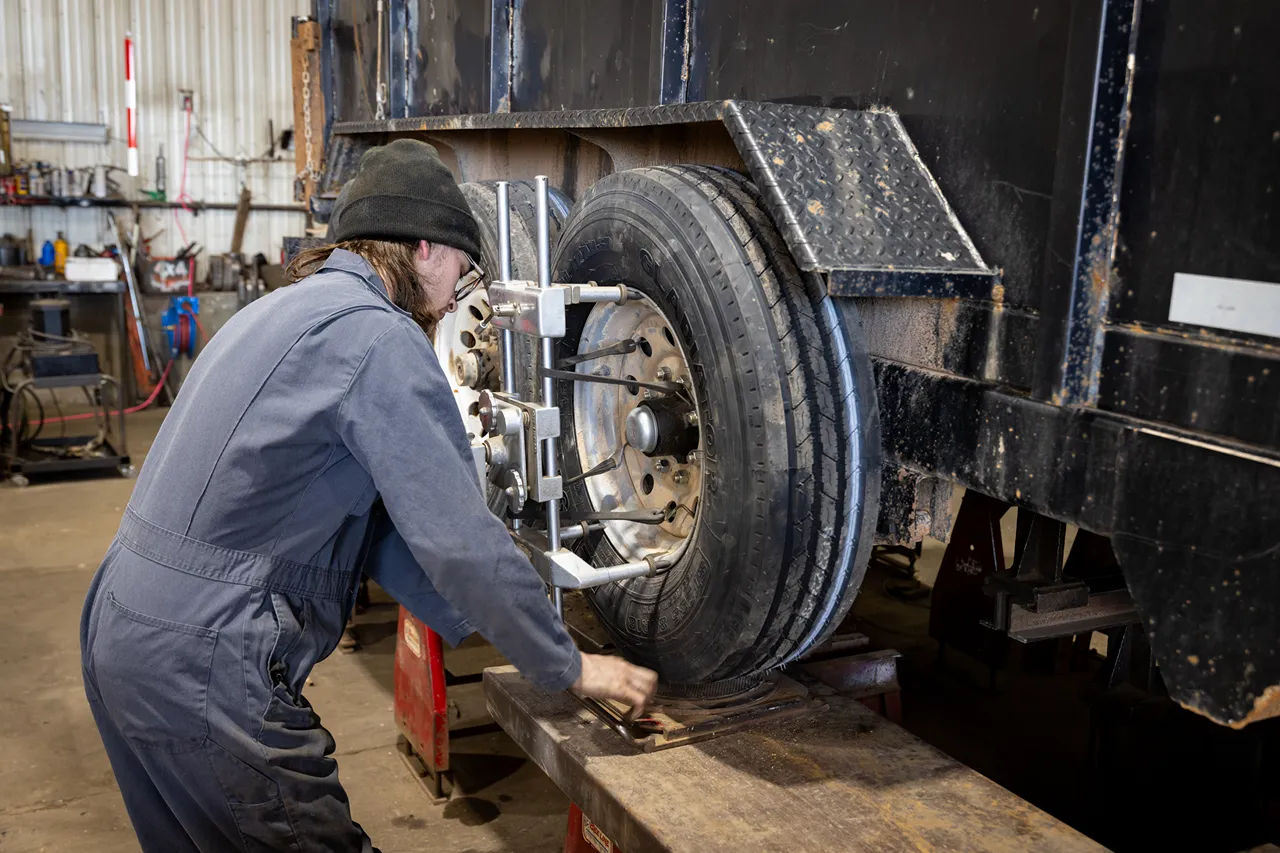 Trailer alignment service with a technician aligning dual trailer wheels using precision alignment equipment.