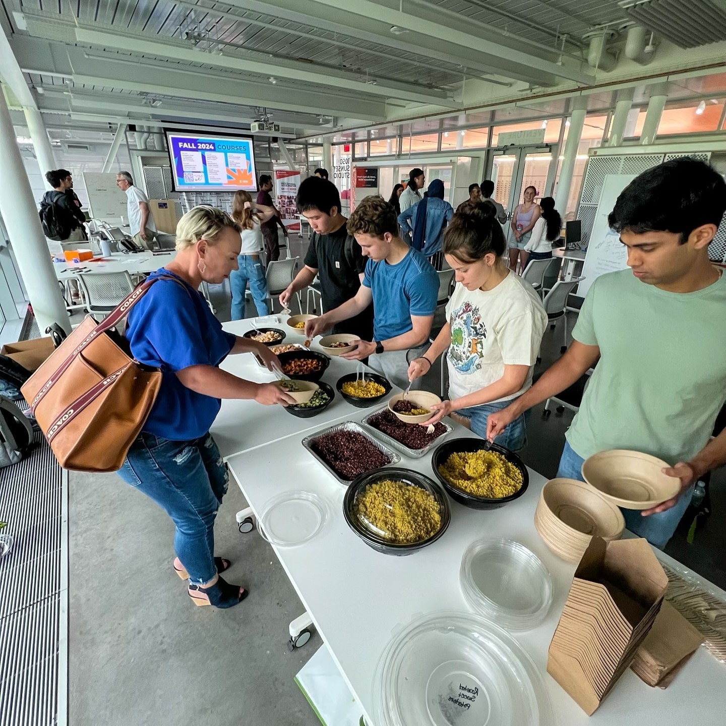 People serving themselves food from a buffet spread by Forage Kitchen catering in a bright, modern room.