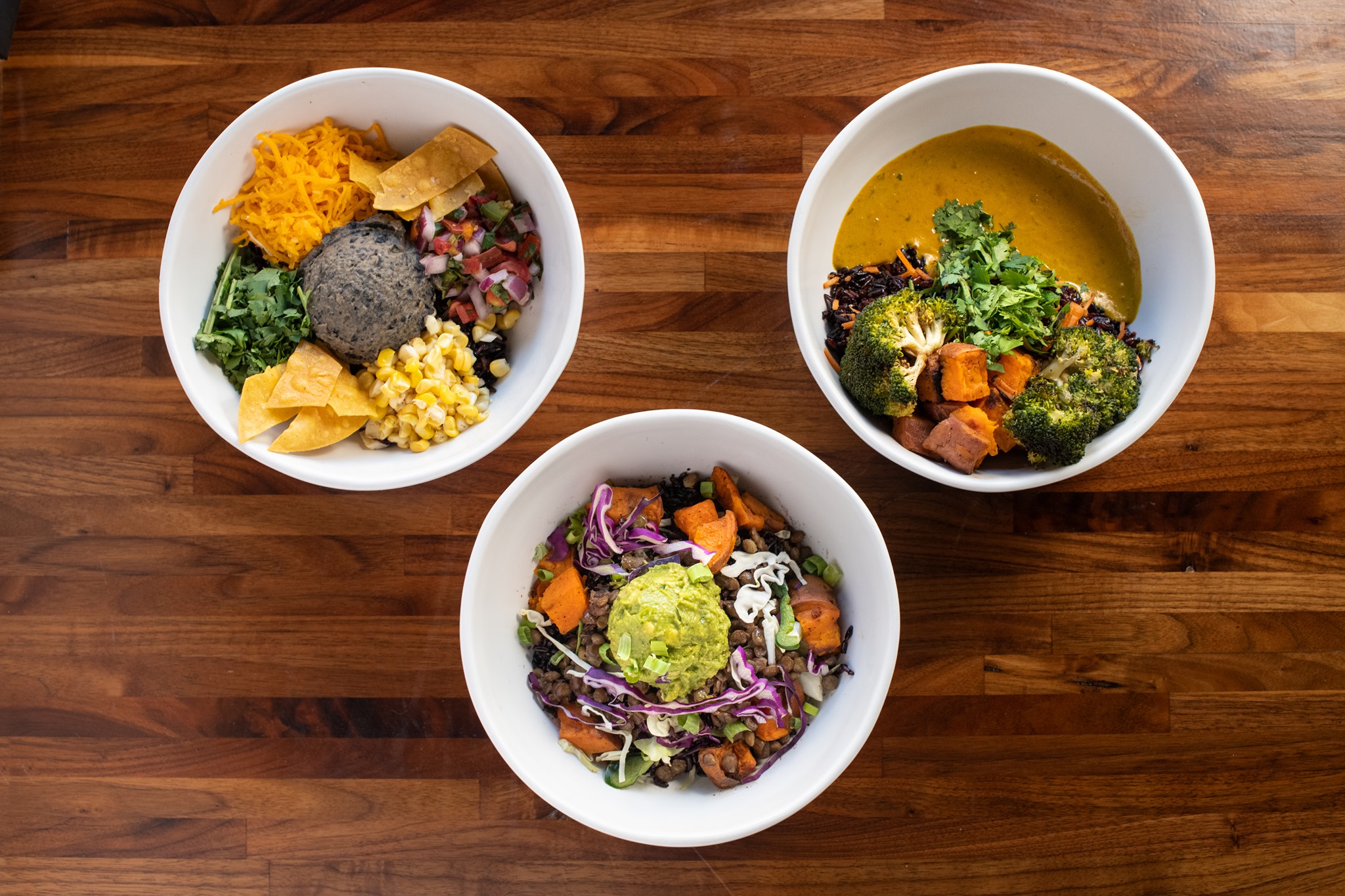 Three colorful summer grain bowls from Forage Kitchen featuring fresh vegetables, grains, and vibrant toppings.