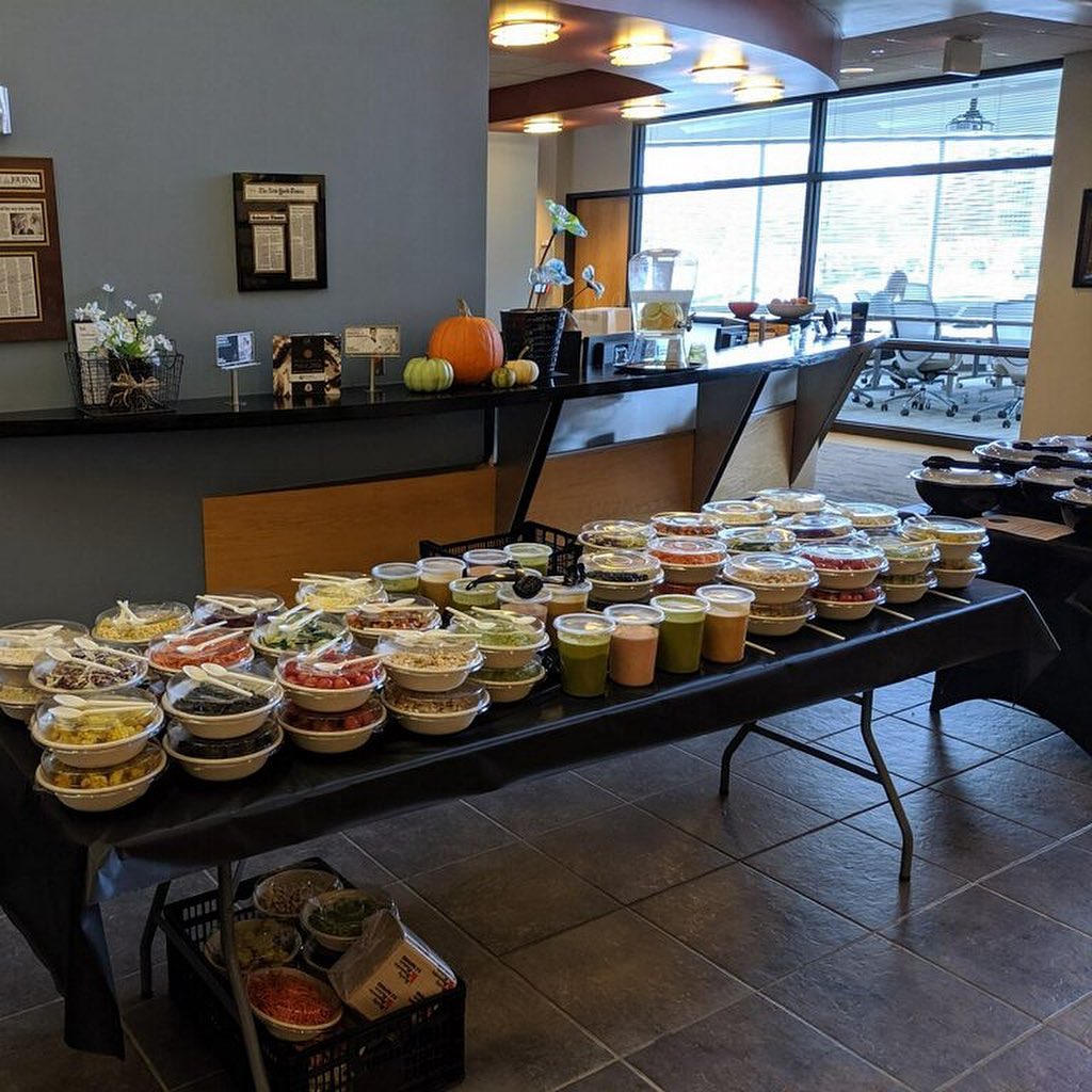 A corporate table piled with Forage Kitchen catering bowls with fall decorations.