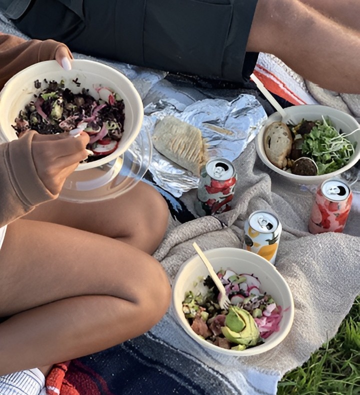 Friends enjoying Forage Kitchen’s healthy grain bowls, wraps, and beverages in a park in Madison.