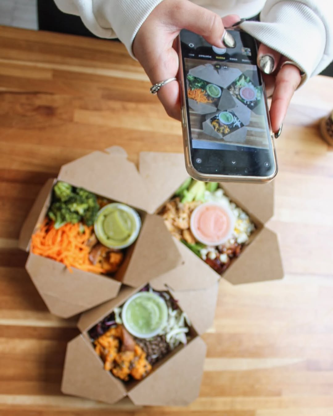 A phone capturing Forage Kitchen’s zero-waste takeout food containers, highlighting sustainable packaging options.