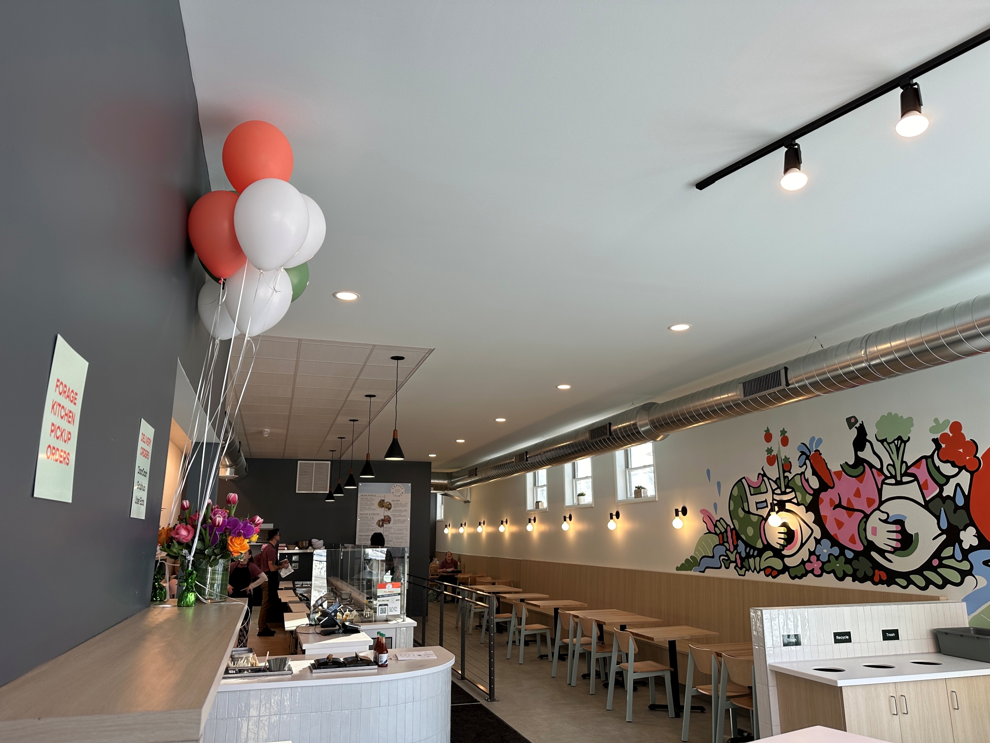 Forage Kitchen restaurant in Whitefish Bay, featuring a bright dining area, a pickup counter, and a colorful mural.
