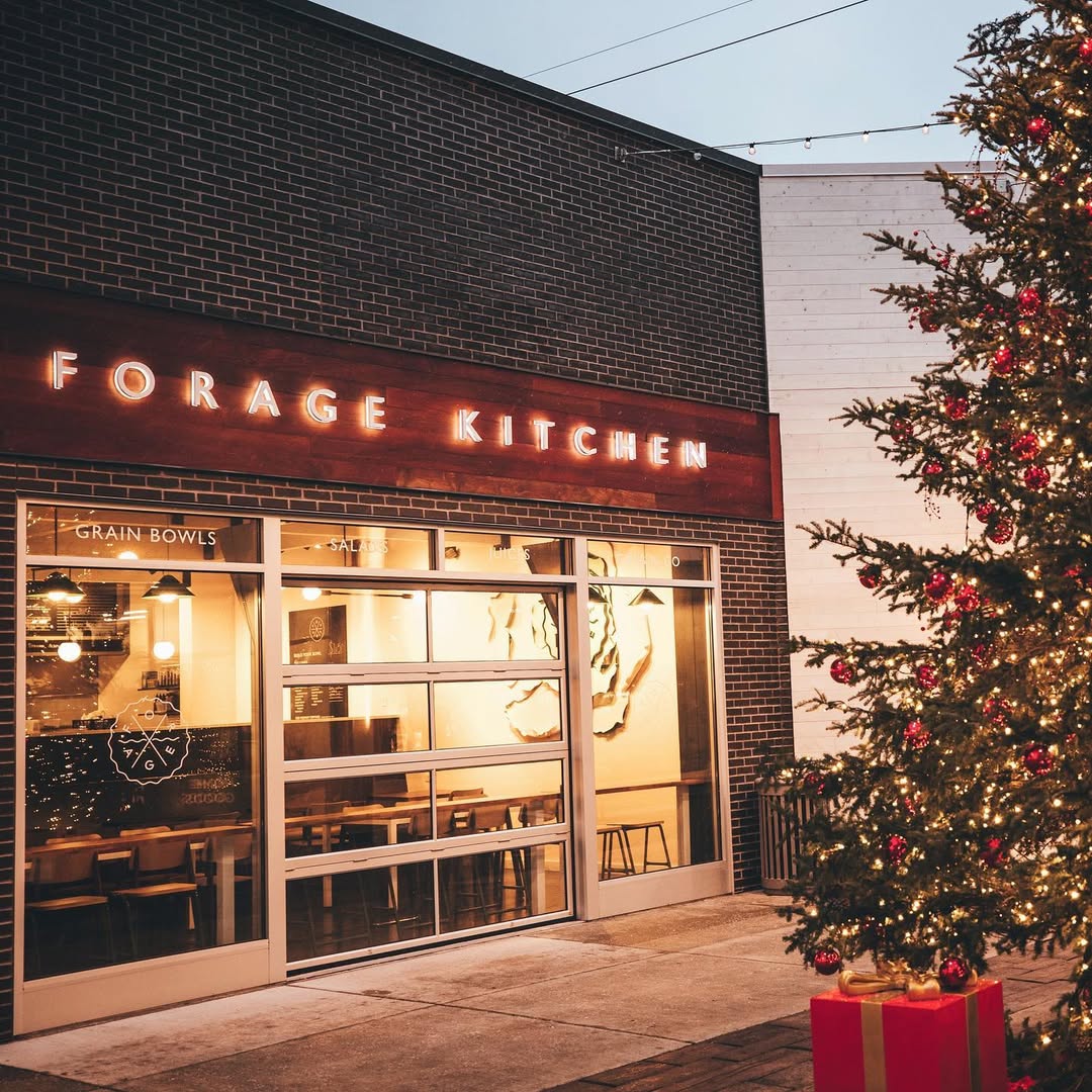 Forage Kitchen storefront at night with a large, beautifully decorated holiday tree glowing just outside the entrance.