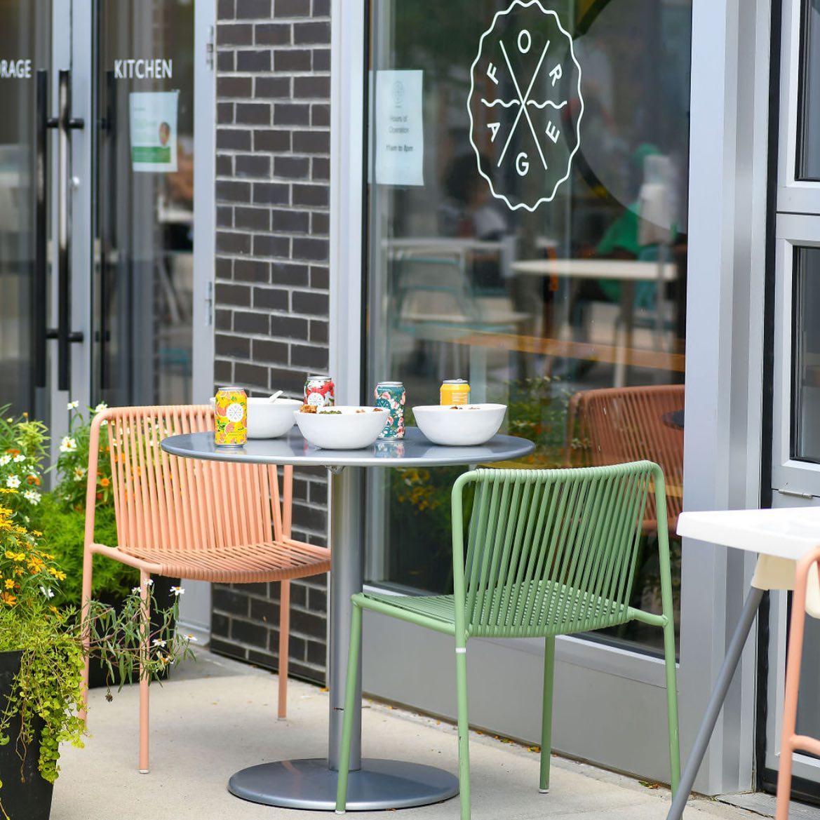  Exterior of a Forage Kitchen Madison with two chairs, bowls, and beverages on a table.