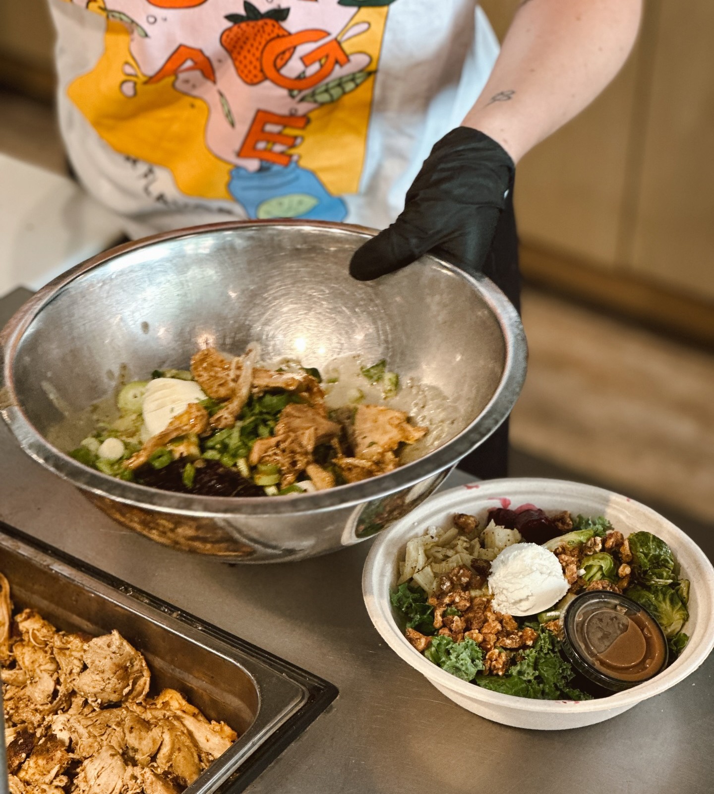 A team member at Forage Kitchen is making a grain bowl, with a bowl ready sitting on the counter.