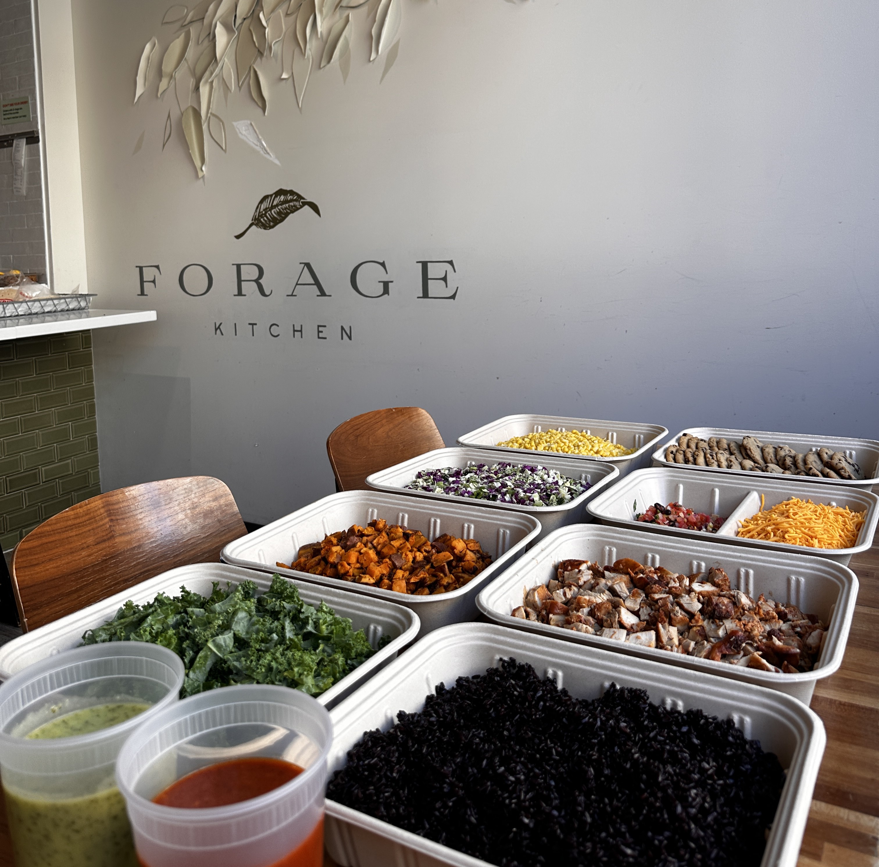 Fresh grain bowl ingredients, including base, greens, proteins, and dressings, catered by Forage Kitchen.