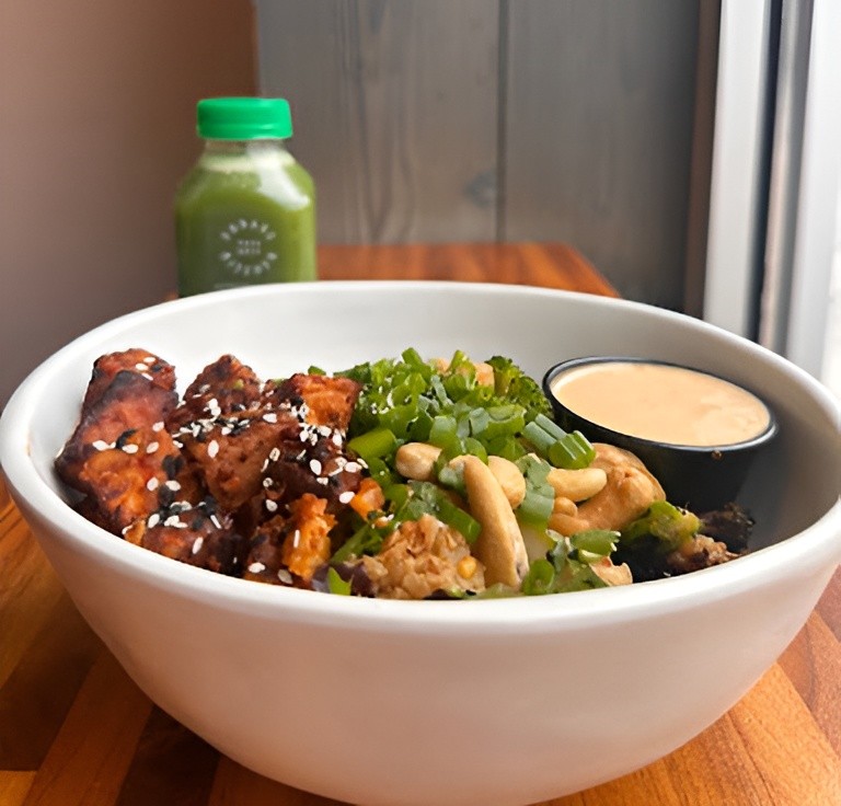 Forage Kitchen Cashew Bowl with veggies, cashews, mixed greens, and Thai vinaigrette, beside a Lean Green bottle.