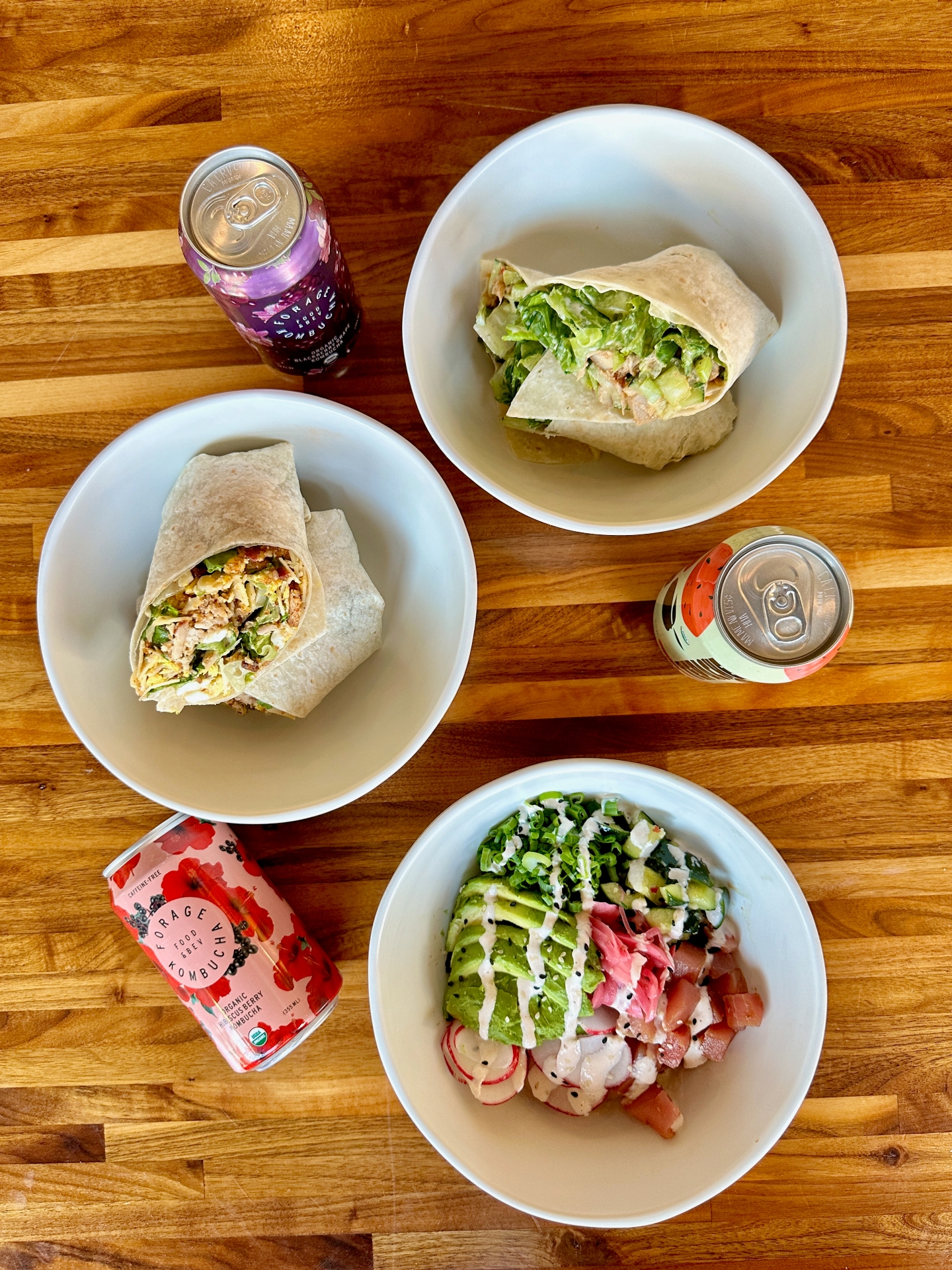 Top-down view of Forage Kitchen spread with wrap sandwiches, beverages, and a grain bowl.