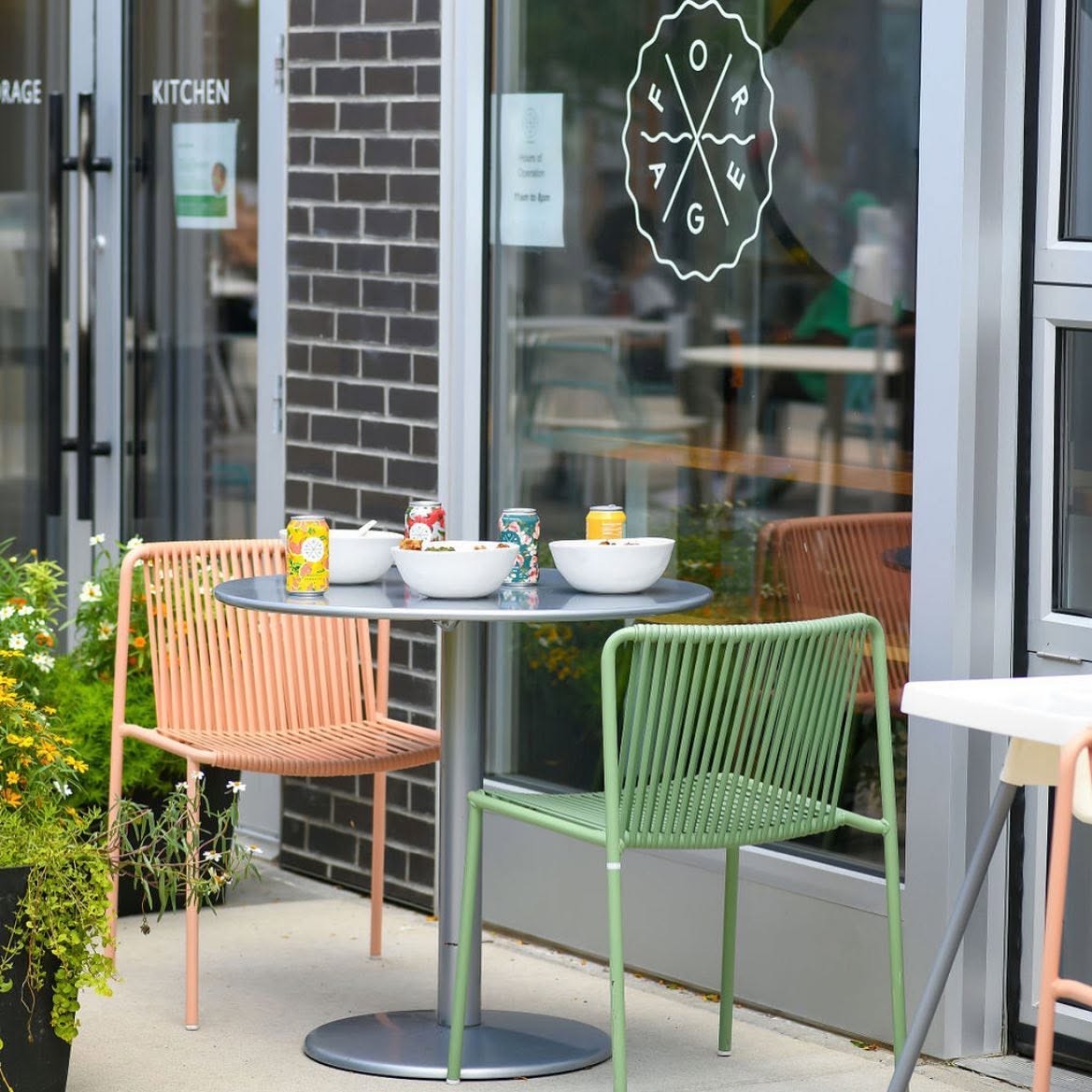 An outdoor patio table set with bowls and canned kombucha and tepache outside a Forage Kitchen restaurant.