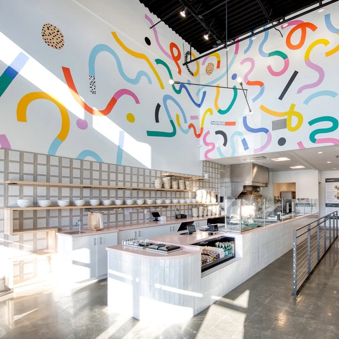 Forage Kitchen Middleton interior featuring a counter and colorful abstract mural walls.