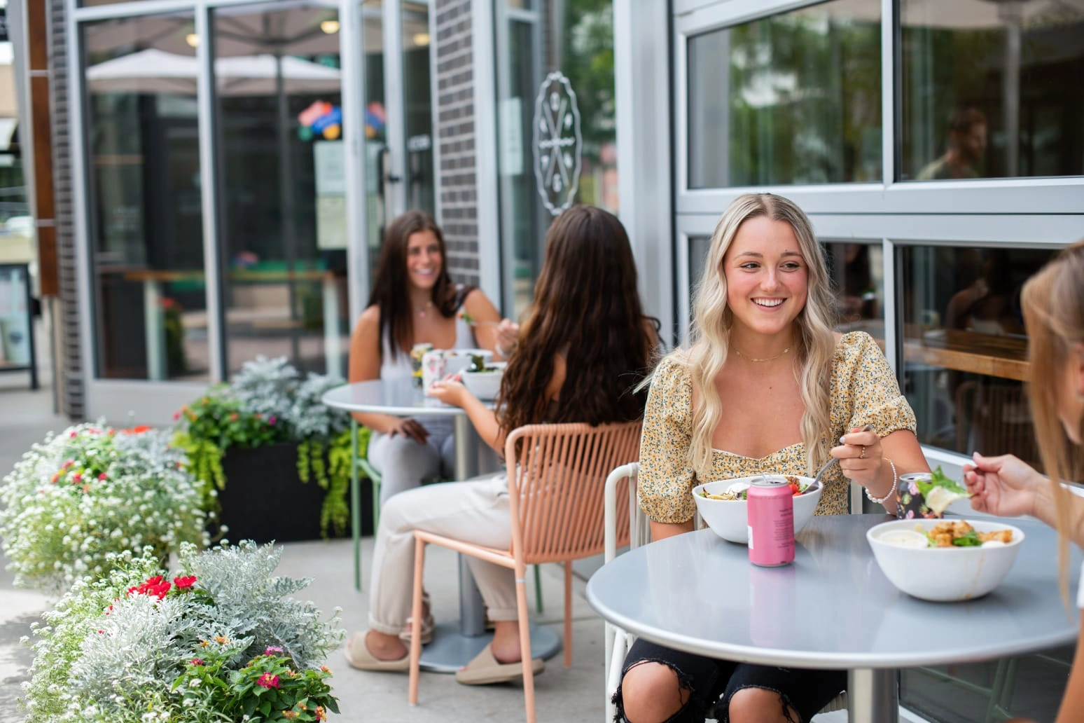 Friends enjoying healthy grain bowls and drinks at an outdoor patio table at Forage Kitchen, Hilldale.
